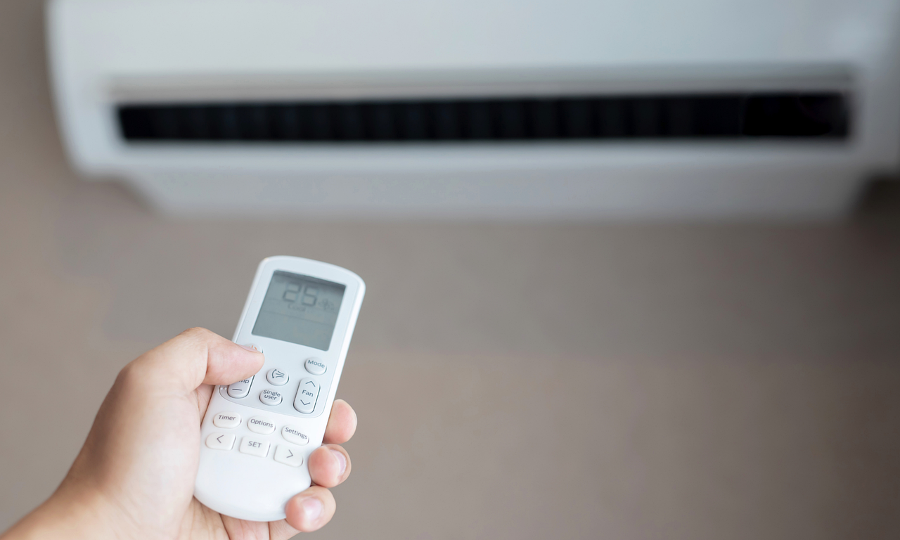 close-up of a hand holding an air conditioner remote